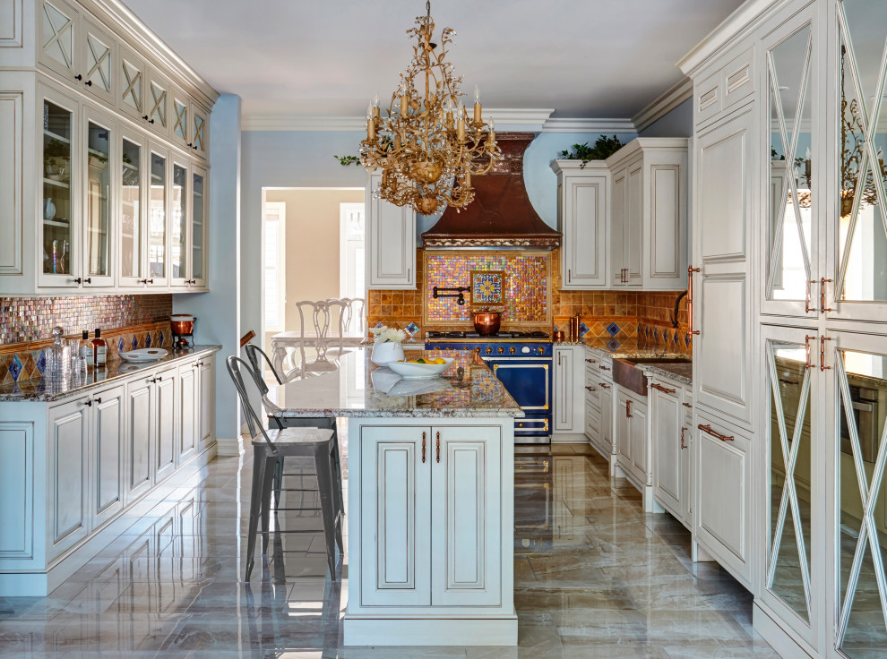 Example of a classic u-shaped beige floor kitchen design in Chicago with a farmhouse sink, raised-panel cabinets, white cabinets, brown backsplash, colored appliances, an island and brown countertops