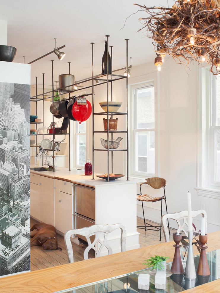 Stilmix Wohnküche mit flächenbündigen Schrankfronten, Küchengeräten aus Edelstahl, hellem Holzboden, Kücheninsel und weißen Schränken in Philadelphia
