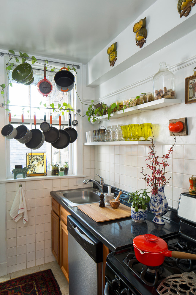 Imagen de cocina lineal ecléctica pequeña sin isla con fregadero encastrado, armarios con paneles empotrados, puertas de armario de madera oscura, salpicadero blanco y electrodomésticos de acero inoxidable