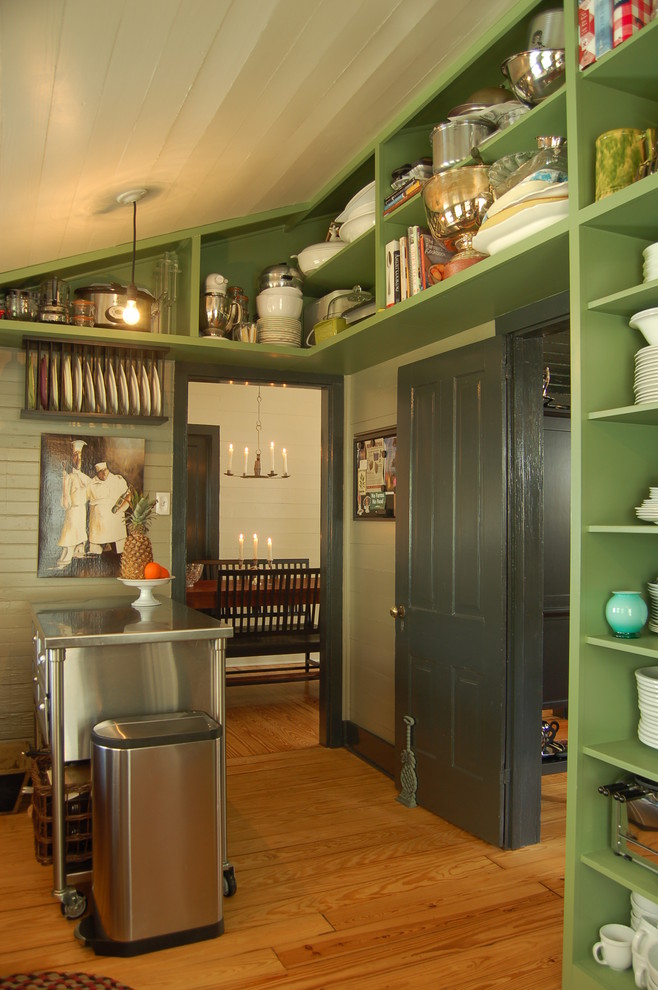 This is an example of an eclectic enclosed kitchen in Austin with stainless steel appliances, open cabinets, green cabinets and stainless steel worktops.