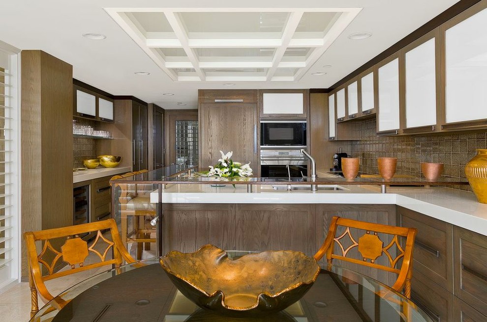 Aménagement d'une cuisine américaine encastrable classique en U et bois brun avec un évier encastré, un placard à porte shaker et une crédence marron.