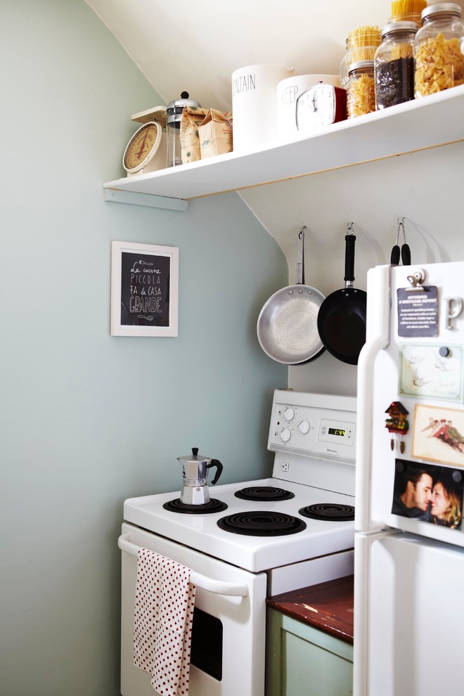 This is an example of a small eclectic enclosed kitchen in Toronto with white appliances.