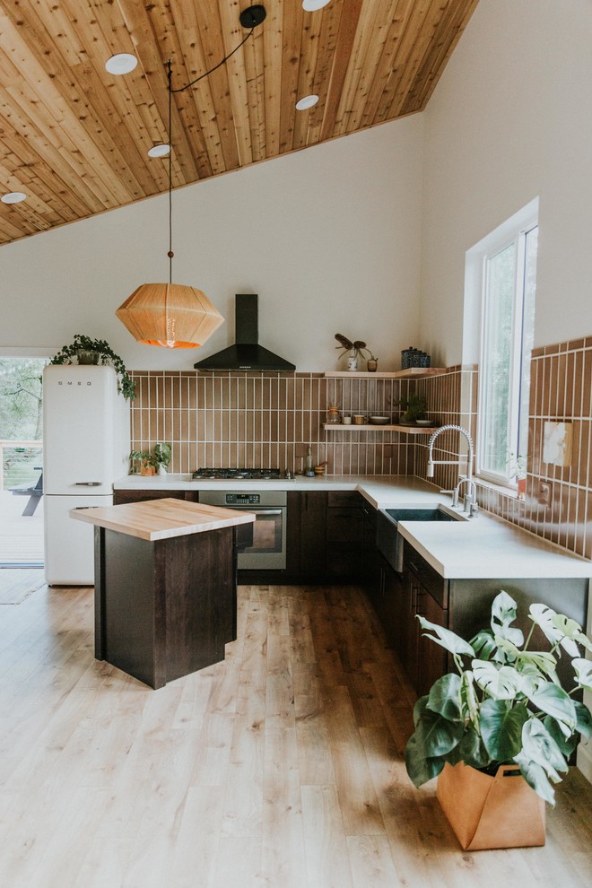 Esempio di una cucina scandinava di medie dimensioni con ante in legno bruno, paraspruzzi marrone, paraspruzzi con piastrelle in ceramica, elettrodomestici in acciaio inossidabile, pavimento in legno massello medio, pavimento marrone e top bianco