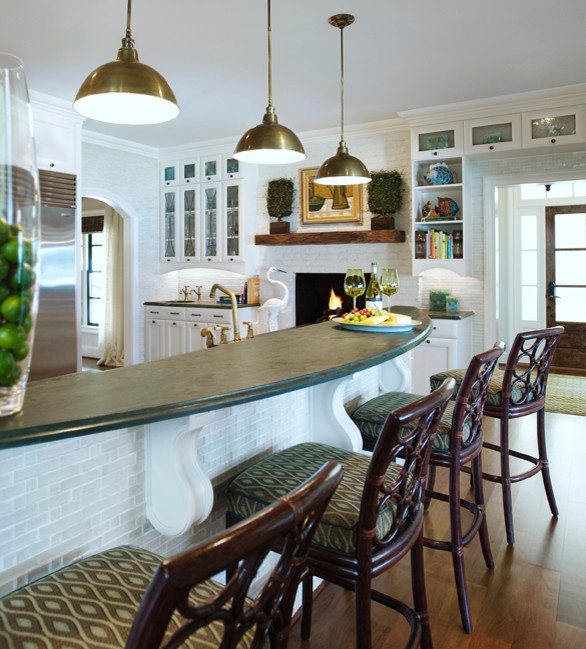 Inredning av ett eklektiskt kök, med en undermonterad diskho, luckor med glaspanel, vita skåp, stänkskydd i tegel, rostfria vitvaror, mellanmörkt trägolv, en köksö, brunt golv, granitbänkskiva och vitt stänkskydd