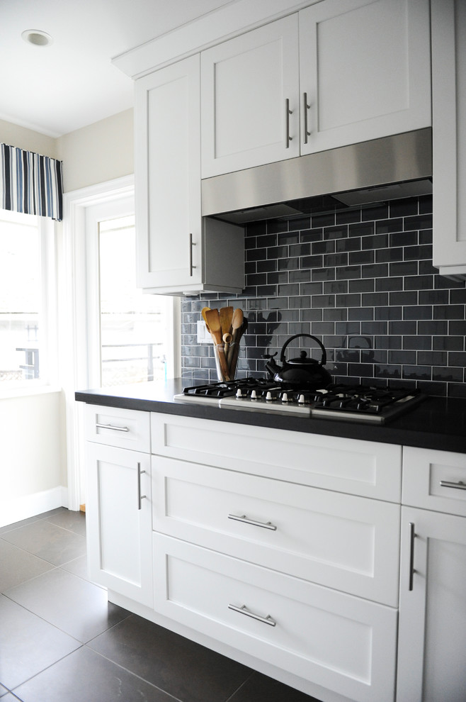 Small transitional galley porcelain tile eat-in kitchen photo in Vancouver with an undermount sink, shaker cabinets, granite countertops, black backsplash, glass tile backsplash, stainless steel appliances and a peninsula