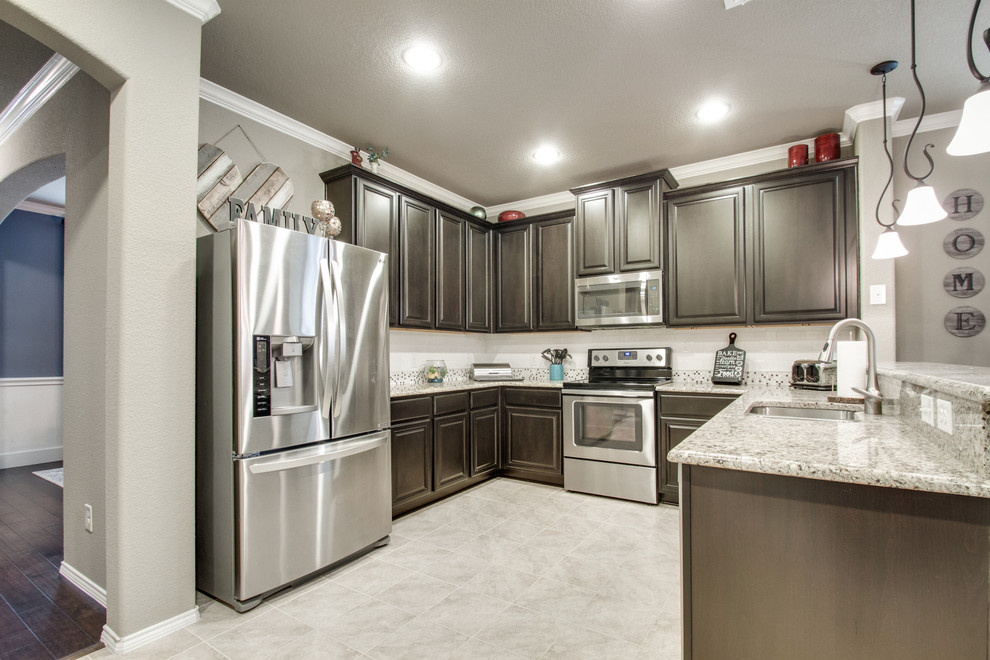 Foto på ett mellanstort eklektiskt grå kök, med en undermonterad diskho, luckor med upphöjd panel, bruna skåp, granitbänkskiva, vitt stänkskydd, stänkskydd i keramik, rostfria vitvaror, klinkergolv i keramik, en halv köksö och grått golv