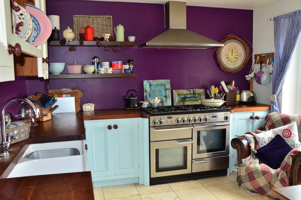 Idée de décoration pour une cuisine américaine champêtre en L de taille moyenne avec un évier posé, un placard à porte shaker, des portes de placard bleues, un plan de travail en bois, un électroménager en acier inoxydable, un sol en carrelage de céramique, aucun îlot et un sol beige.