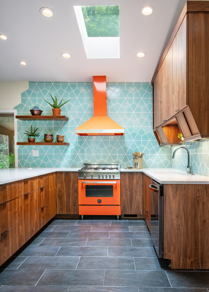 Eklektisk inredning av ett stort vit vitt kök, med en undermonterad diskho, skåp i mellenmörkt trä, blått stänkskydd, stänkskydd i keramik, färgglada vitvaror, en halv köksö och grått golv