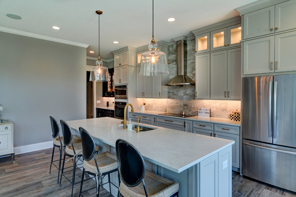 Inspiration for a mid-sized eclectic single-wall vinyl floor and brown floor eat-in kitchen remodel in Indianapolis with a drop-in sink, shaker cabinets, beige cabinets, granite countertops, gray backsplash, ceramic backsplash, stainless steel appliances, an island and white countertops