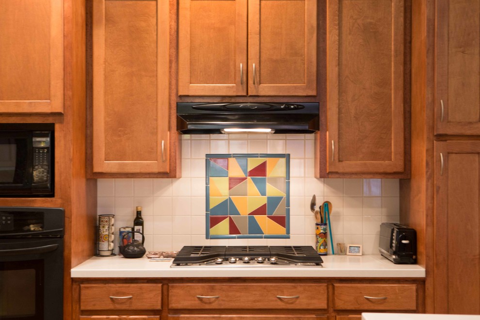 Foto de cocina comedor bohemia con salpicadero blanco, salpicadero de azulejos de cerámica, electrodomésticos negros y una isla