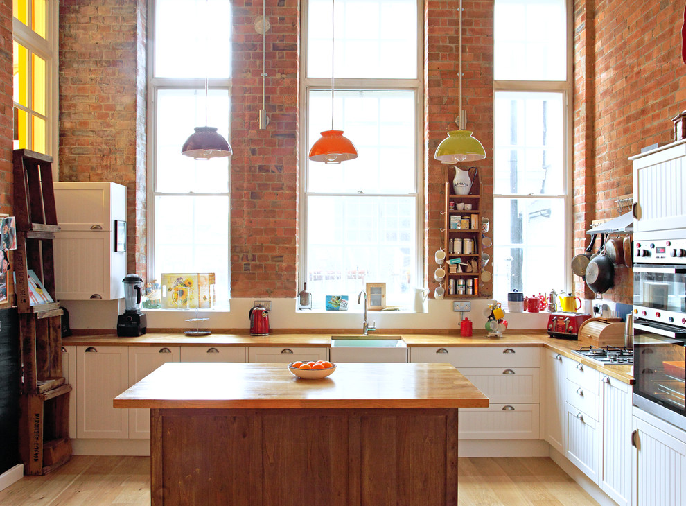 Foto på ett mellanstort eklektiskt kök, med luckor med infälld panel, vita skåp, träbänkskiva, stänkskydd med metallisk yta, rostfria vitvaror och en köksö
