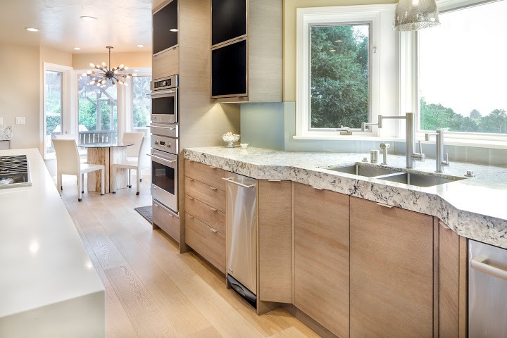Photo of a large bohemian kitchen/diner in San Francisco with a submerged sink, flat-panel cabinets, light wood cabinets, engineered stone countertops and stainless steel appliances.