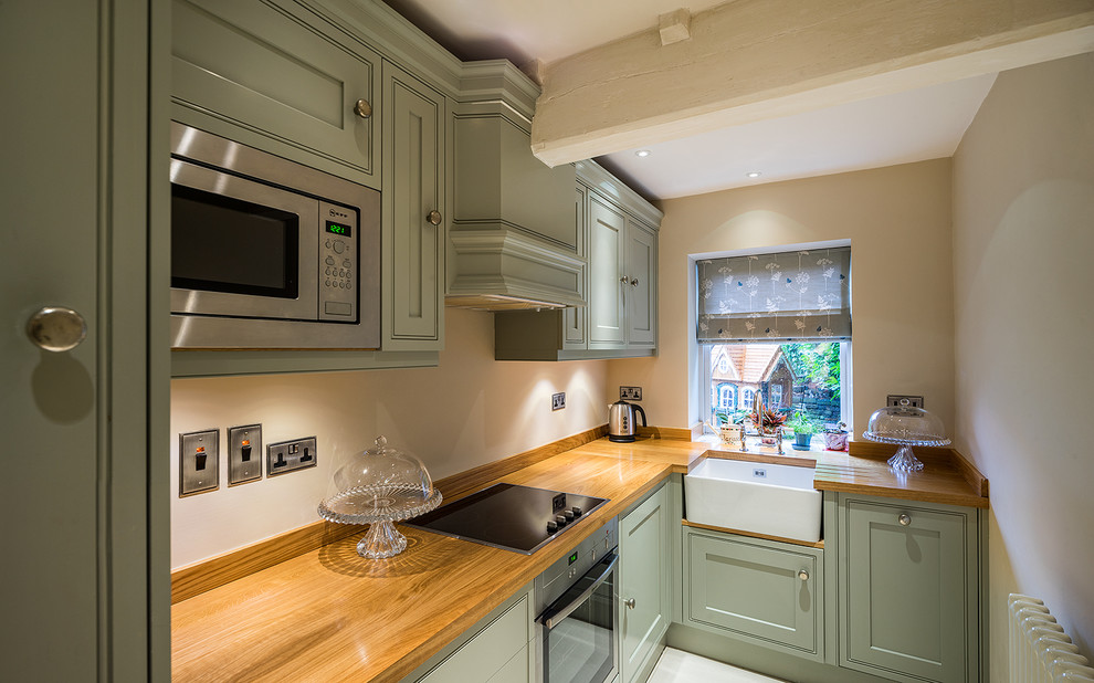 Inspiration for a small transitional l-shaped enclosed kitchen remodel in Other with a farmhouse sink, shaker cabinets, green cabinets, wood countertops, stainless steel appliances and no island
