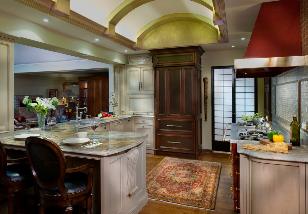 Inspiration for a small eclectic u-shaped medium tone wood floor eat-in kitchen remodel in Other with an undermount sink, beaded inset cabinets, distressed cabinets, quartzite countertops, beige backsplash, paneled appliances, a peninsula and glass tile backsplash