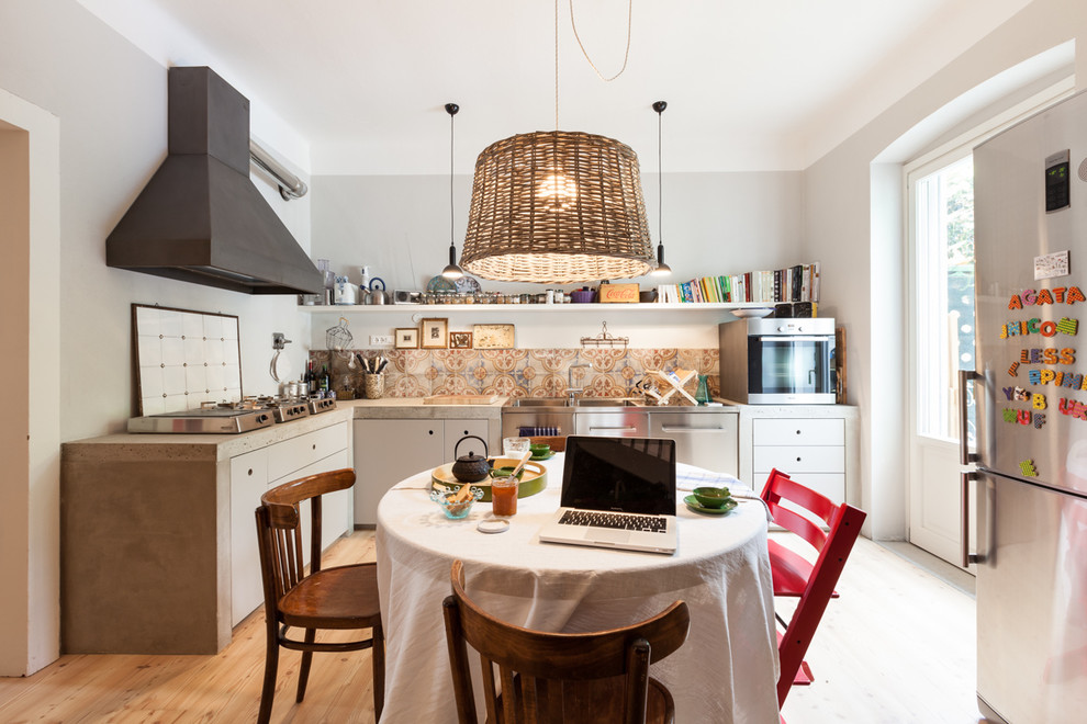 Eclectic u-shaped kitchen/diner in Other with flat-panel cabinets, white cabinets, concrete worktops, stainless steel appliances and light hardwood flooring.