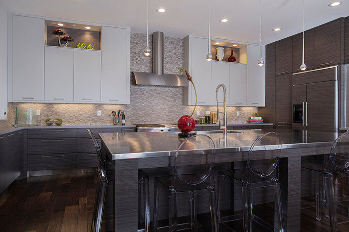 Example of a mid-sized transitional u-shaped dark wood floor eat-in kitchen design in New Orleans with an undermount sink, flat-panel cabinets, gray cabinets, stainless steel countertops, multicolored backsplash, glass sheet backsplash, stainless steel appliances and an island
