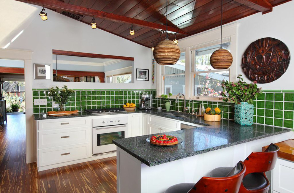Immagine di una cucina ad U tropicale con lavello sottopiano, ante in stile shaker, ante bianche, paraspruzzi verde e penisola