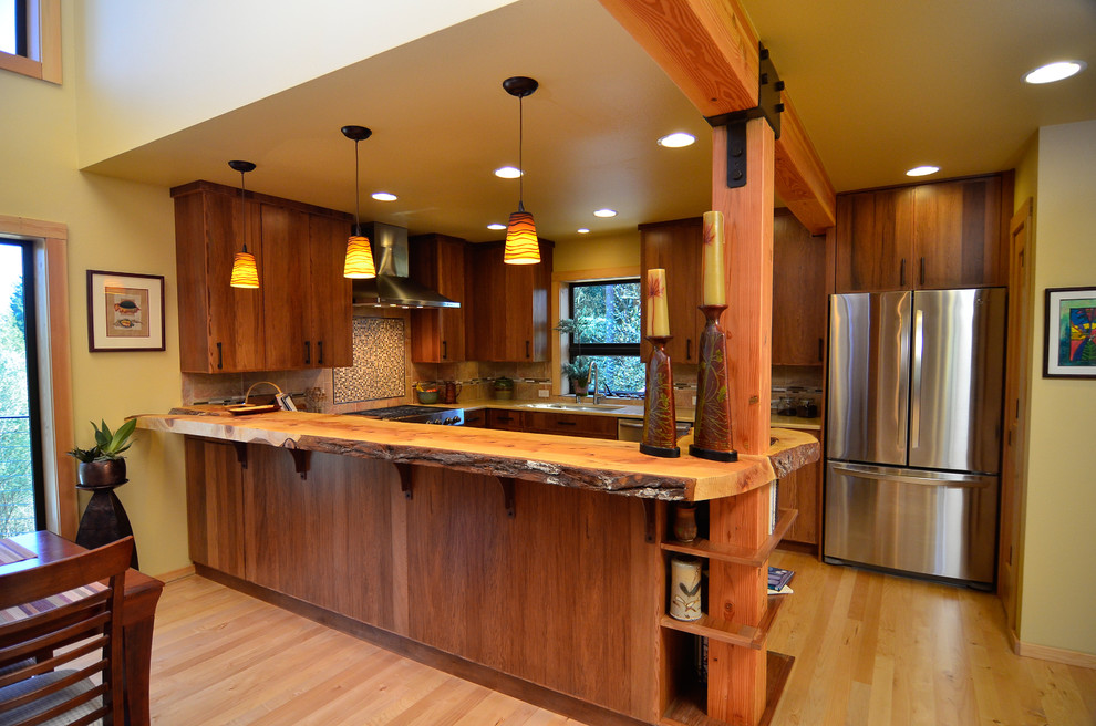 Foto på ett funkis kök, med en undermonterad diskho, släta luckor, skåp i mellenmörkt trä, träbänkskiva och rostfria vitvaror