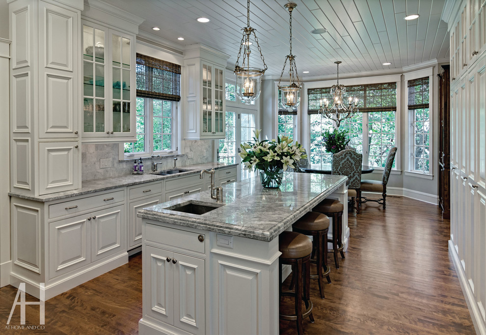 Eat-in kitchen - transitional eat-in kitchen idea in Minneapolis with raised-panel cabinets, white cabinets, marble countertops, white backsplash and an island