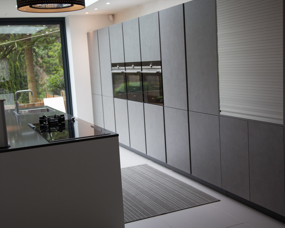 Esempio di una grande cucina design con lavello a vasca singola, ante lisce, ante grigie, top in quarzite, elettrodomestici neri, pavimento in gres porcellanato e pavimento grigio