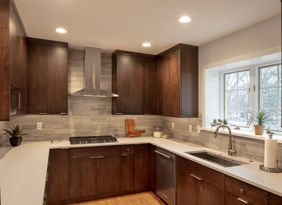 Mid-sized trendy u-shaped light wood floor kitchen photo in St Louis with a single-bowl sink, flat-panel cabinets, dark wood cabinets, quartz countertops, gray backsplash, subway tile backsplash, stainless steel appliances, a peninsula and white countertops
