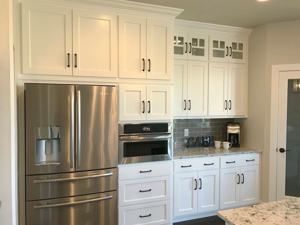 Large arts and crafts single-wall vinyl floor and brown floor open concept kitchen photo in Other with shaker cabinets, white cabinets, granite countertops, gray backsplash, subway tile backsplash, stainless steel appliances and an island