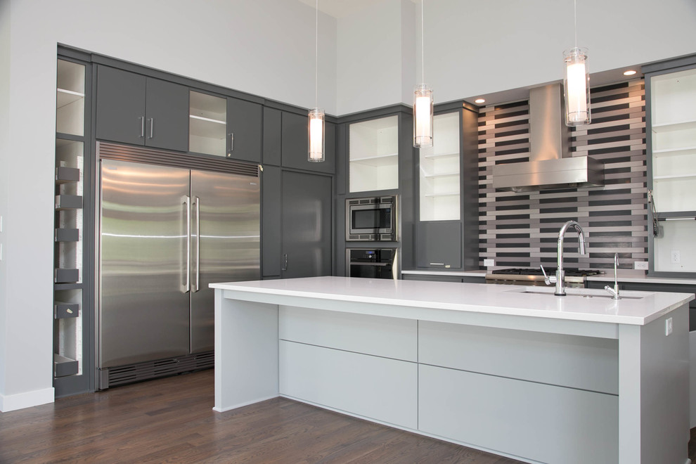 Photo of a modern l-shaped kitchen/diner in Minneapolis with a built-in sink, flat-panel cabinets, grey cabinets, granite worktops, grey splashback, ceramic splashback, stainless steel appliances, dark hardwood flooring and an island.