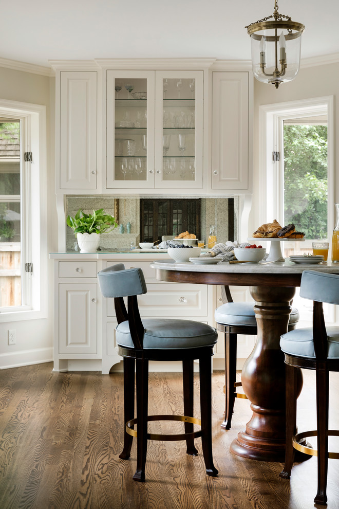 Foto di una grande cucina tradizionale con ante di vetro, ante bianche, top in marmo, paraspruzzi a specchio, pavimento in legno massello medio, pavimento marrone e top bianco