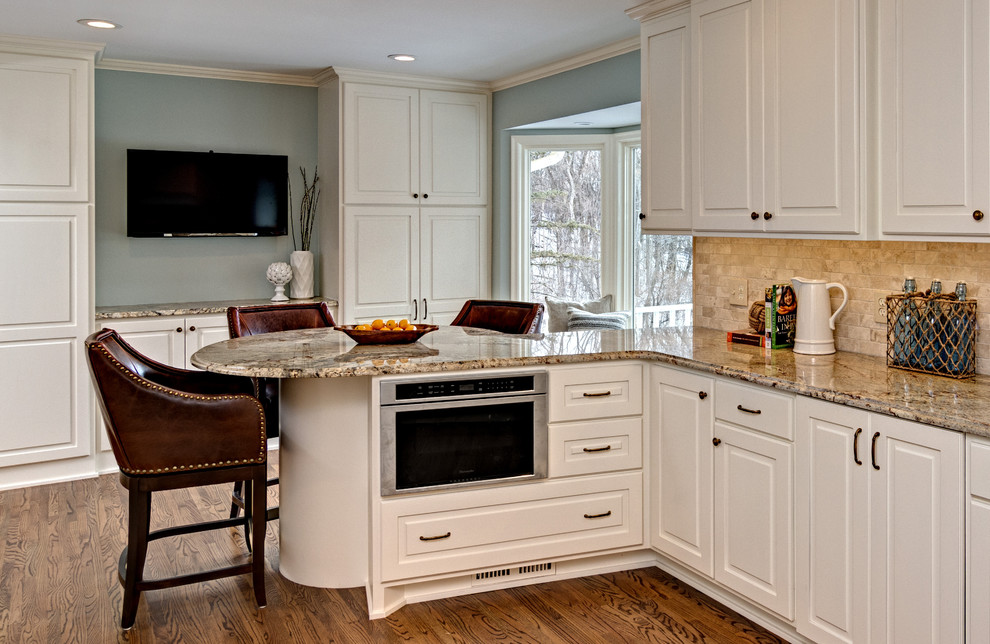 Exempel på ett avskilt, mellanstort klassiskt u-kök, med vita skåp, granitbänkskiva, beige stänkskydd, stänkskydd i keramik, rostfria vitvaror, mellanmörkt trägolv och en halv köksö