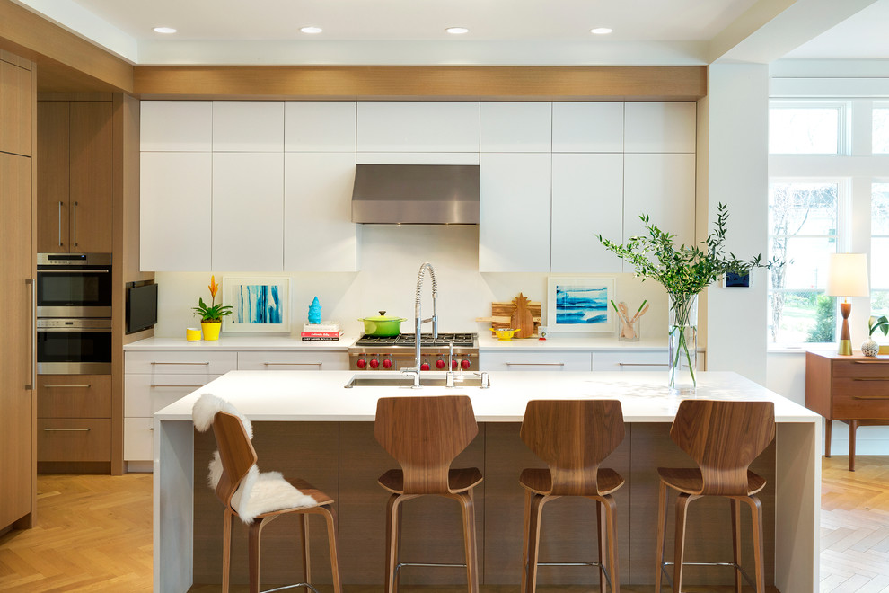 Foto di una cucina moderna con lavello sottopiano, ante lisce, ante bianche, top in superficie solida, paraspruzzi bianco, elettrodomestici da incasso e parquet chiaro