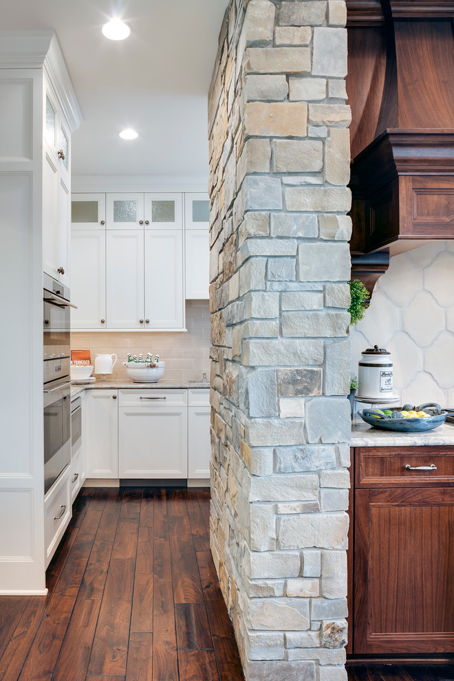 This is an example of a traditional open plan kitchen in Minneapolis with white cabinets, quartz worktops, beige splashback, cement tile splashback, integrated appliances, dark hardwood flooring and an island.