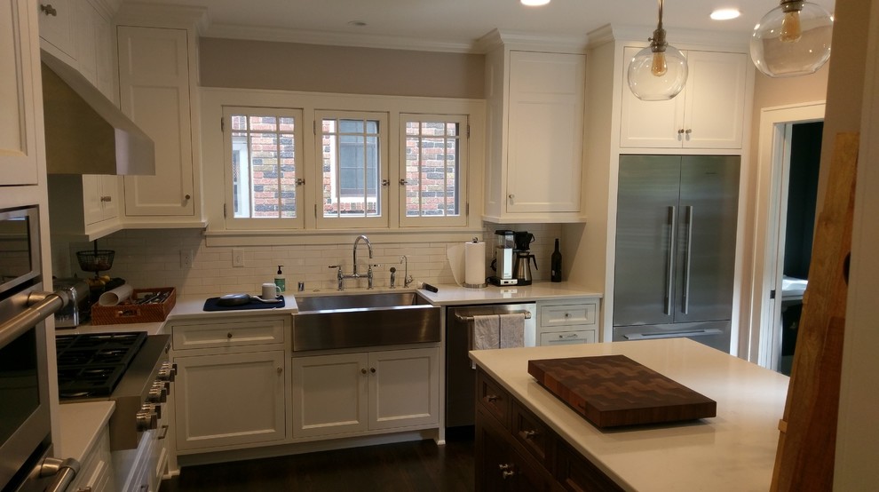 Bild på ett avskilt, litet vintage l-kök, med en rustik diskho, luckor med profilerade fronter, vita skåp, bänkskiva i kvarts, vitt stänkskydd, stänkskydd i porslinskakel, rostfria vitvaror, mörkt trägolv, en halv köksö och brunt golv