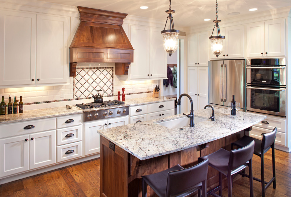 Photo of a traditional l-shaped kitchen in Minneapolis with a submerged sink, recessed-panel cabinets, white cabinets, white splashback, metro tiled splashback and stainless steel appliances.