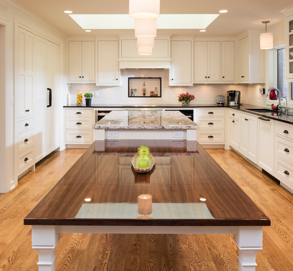 Design ideas for an expansive traditional u-shaped kitchen/diner in Minneapolis with a double-bowl sink, recessed-panel cabinets, white cabinets, granite worktops, white splashback, ceramic splashback, stainless steel appliances, medium hardwood flooring and an island.