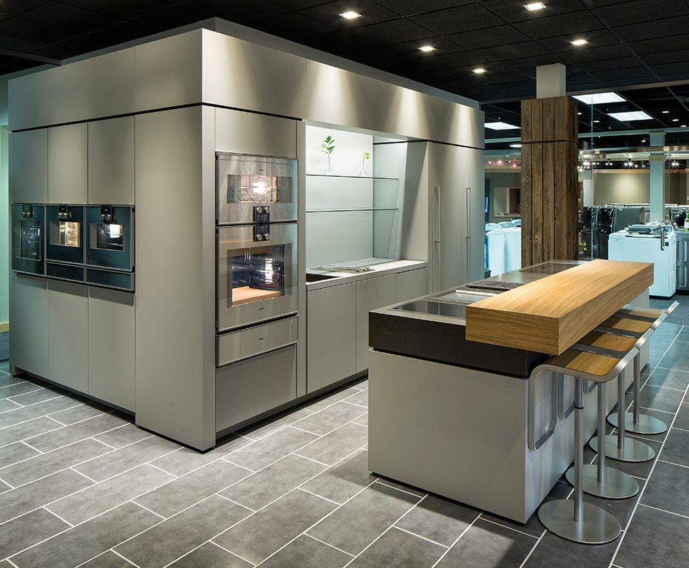 Cette image montre une cuisine encastrable minimaliste de taille moyenne avec un placard à porte plane, des portes de placard grises, un sol en carrelage de céramique et îlot.