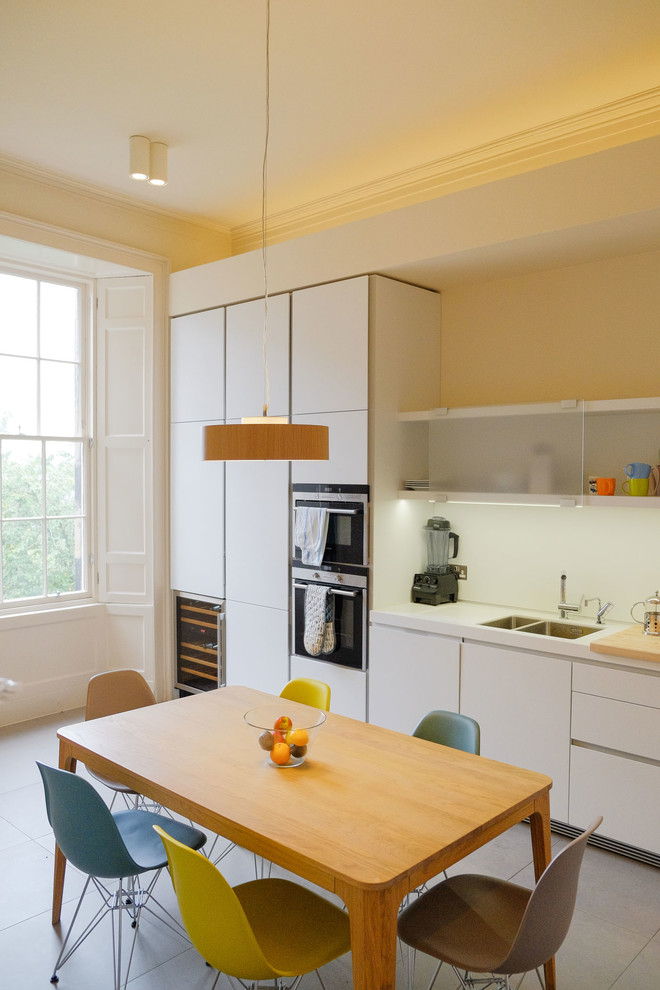 Inspiration for a scandinavian eat-in kitchen remodel in Edinburgh with an undermount sink, flat-panel cabinets, white cabinets and white backsplash