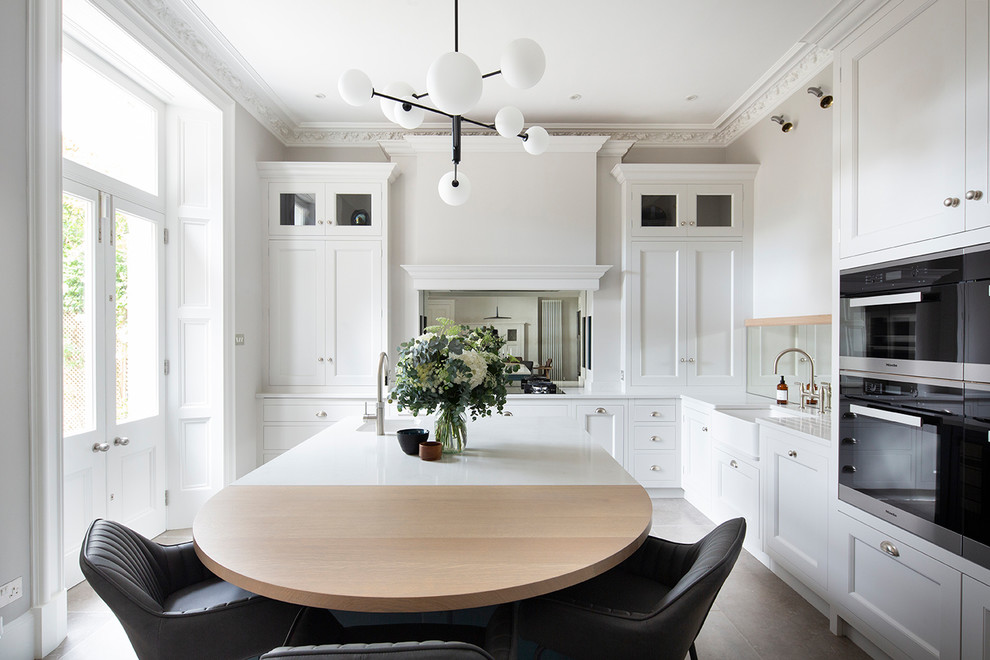 Inspiration for a large eclectic l-shaped kitchen/diner in Edinburgh with a belfast sink, beaded cabinets, white cabinets, quartz worktops, mirror splashback, stainless steel appliances, an island, beige floors and white worktops.