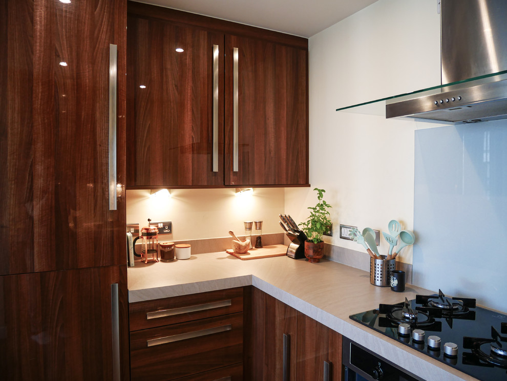 Inredning av ett minimalistiskt mellanstort grå grått kök, med en integrerad diskho, släta luckor, bruna skåp, laminatbänkskiva, grått stänkskydd, svarta vitvaror, vinylgolv och brunt golv
