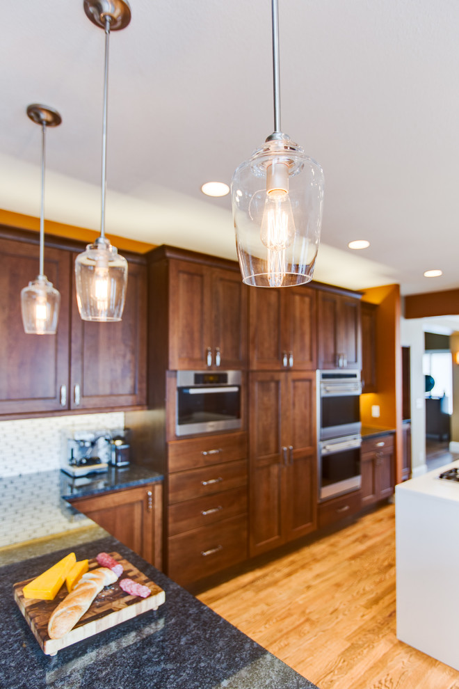 Inspiration for a large transitional u-shaped medium tone wood floor eat-in kitchen remodel in Denver with a single-bowl sink, shaker cabinets, brown cabinets, quartz countertops, white backsplash, mosaic tile backsplash, colored appliances and an island
