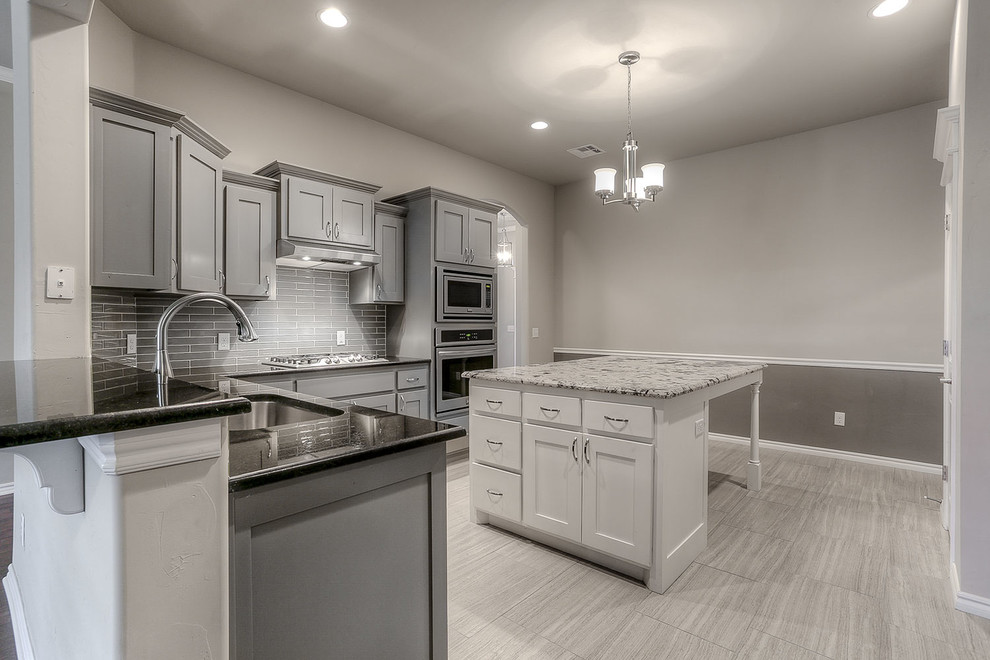 Enclosed kitchen - mid-sized transitional l-shaped enclosed kitchen idea in Oklahoma City with an undermount sink, shaker cabinets, gray cabinets, granite countertops, gray backsplash, ceramic backsplash, stainless steel appliances and an island
