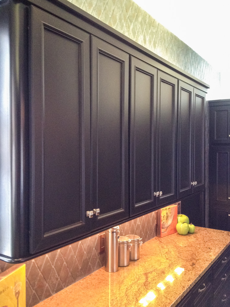 Modern inredning av ett stort kök, med en undermonterad diskho, luckor med infälld panel, svarta skåp, granitbänkskiva, blått stänkskydd, rostfria vitvaror, skiffergolv och en köksö