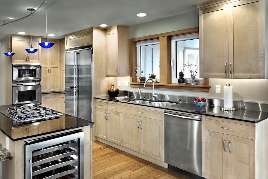Design ideas for a medium sized traditional l-shaped kitchen/diner in Seattle with a submerged sink, shaker cabinets, light wood cabinets, engineered stone countertops, blue splashback, stainless steel appliances, light hardwood flooring and an island.