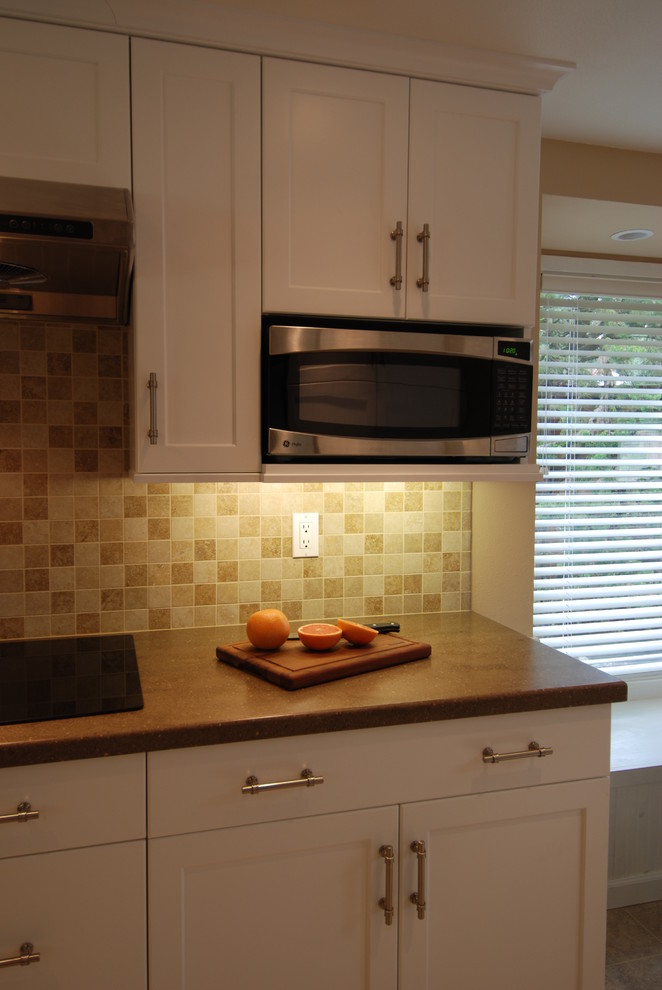 Immagine di una cucina chic di medie dimensioni con ante in stile shaker, ante bianche, top in superficie solida, paraspruzzi beige, paraspruzzi in gres porcellanato e elettrodomestici in acciaio inossidabile