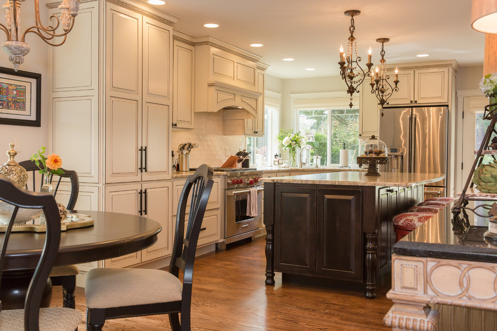 Eat-in kitchen - large traditional l-shaped medium tone wood floor eat-in kitchen idea in Seattle with an undermount sink, raised-panel cabinets, white cabinets, granite countertops, white backsplash, ceramic backsplash, stainless steel appliances and an island