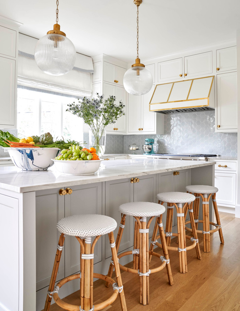Klassische Küche in L-Form mit Schrankfronten im Shaker-Stil, weißen Schränken, Küchenrückwand in Grau, hellem Holzboden, Kücheninsel und weißer Arbeitsplatte in Dallas