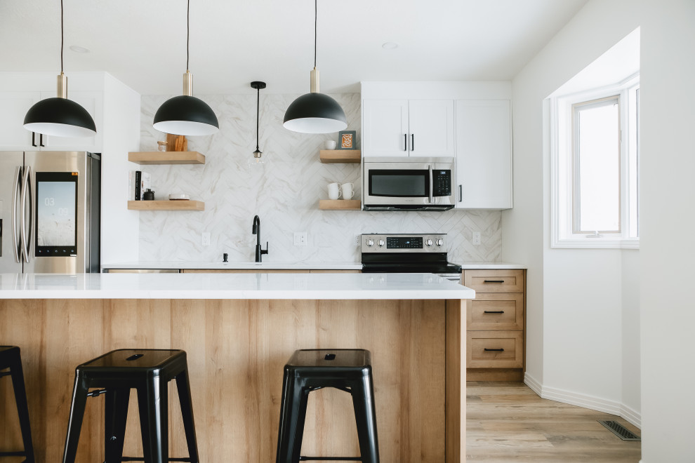 Example of a transitional single-wall medium tone wood floor and brown floor kitchen design in Edmonton with an undermount sink, shaker cabinets, medium tone wood cabinets, multicolored backsplash, stainless steel appliances, an island and white countertops
