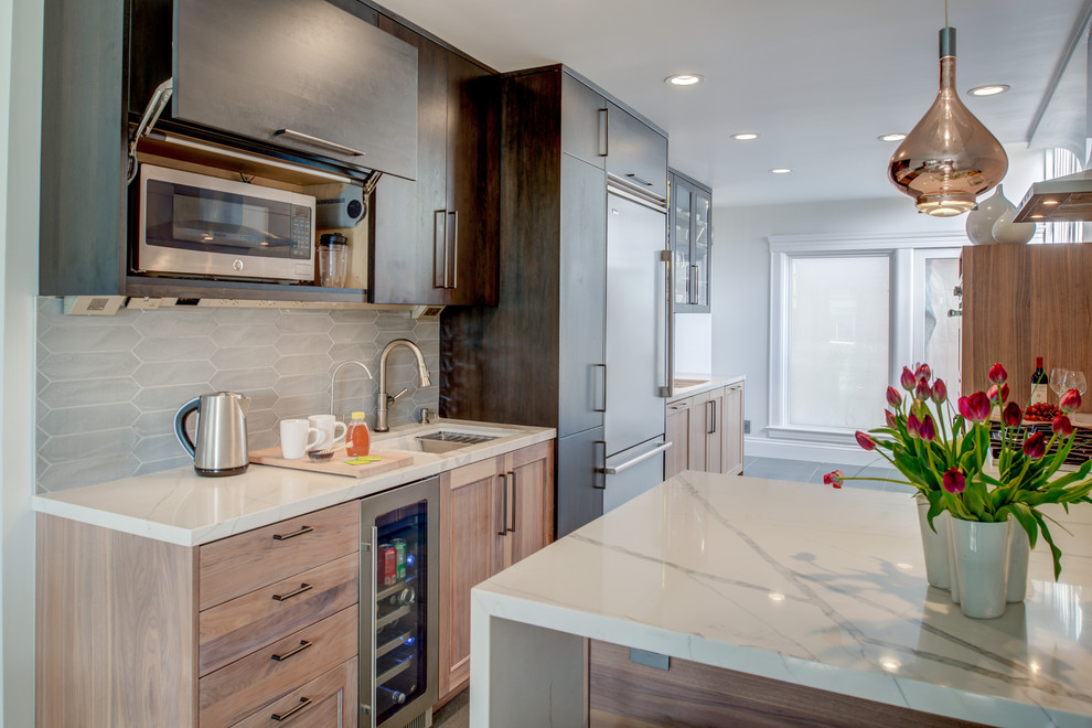 Photo of a large contemporary l-shaped kitchen/diner in San Francisco with a submerged sink, shaker cabinets, medium wood cabinets, engineered stone countertops, white splashback, stainless steel appliances and white worktops.