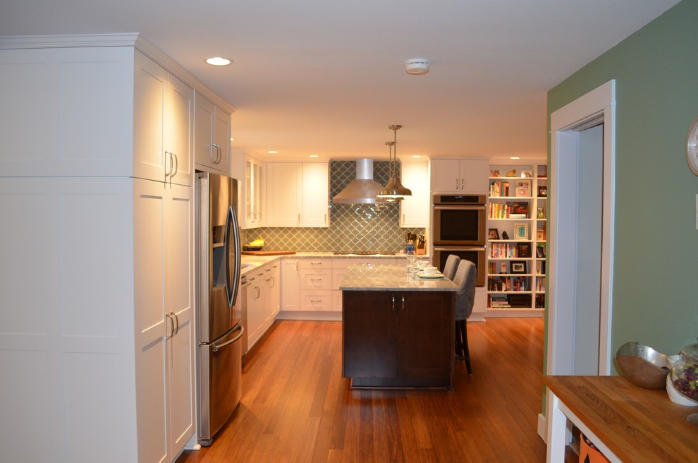 This is an example of a large classic l-shaped open plan kitchen in Seattle with shaker cabinets, white cabinets, quartz worktops, blue splashback, glass tiled splashback, stainless steel appliances, bamboo flooring, an island, a submerged sink and brown floors.