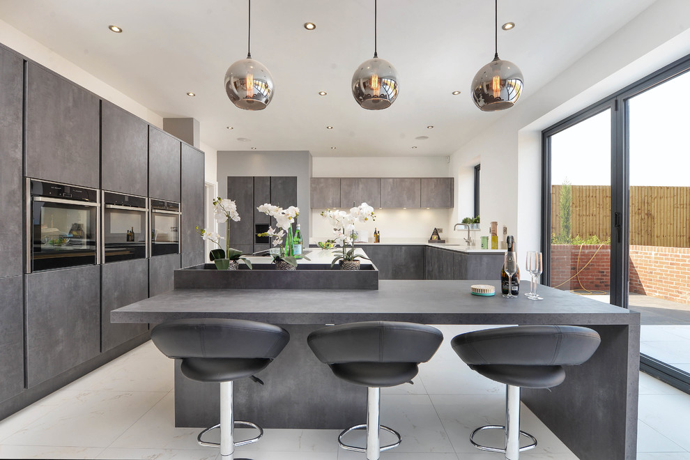Foto di un cucina con isola centrale minimal con ante lisce, lavello sottopiano, ante grigie, paraspruzzi bianco, pavimento bianco e top grigio