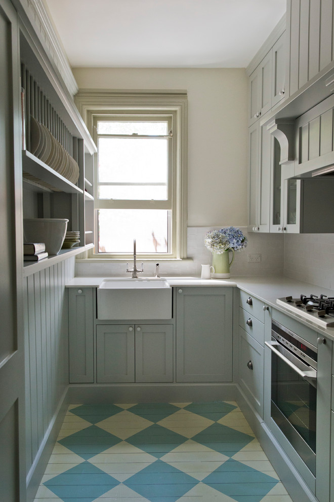 Klassisk inredning av ett mellanstort kök, med en rustik diskho, skåp i shakerstil, grå skåp, bänkskiva i kvarts, vitt stänkskydd, stänkskydd i keramik, rostfria vitvaror och målat trägolv